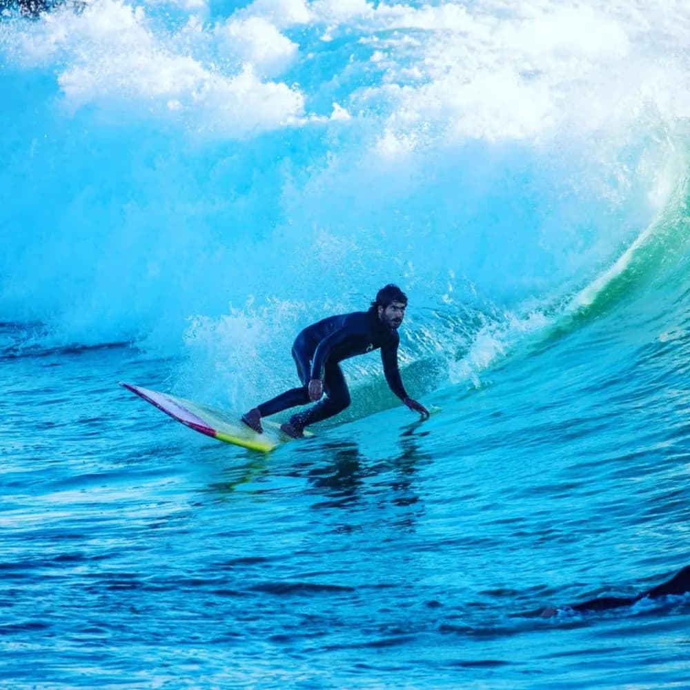 Un surfeur accroupi dans un tube d’un bleu vif.