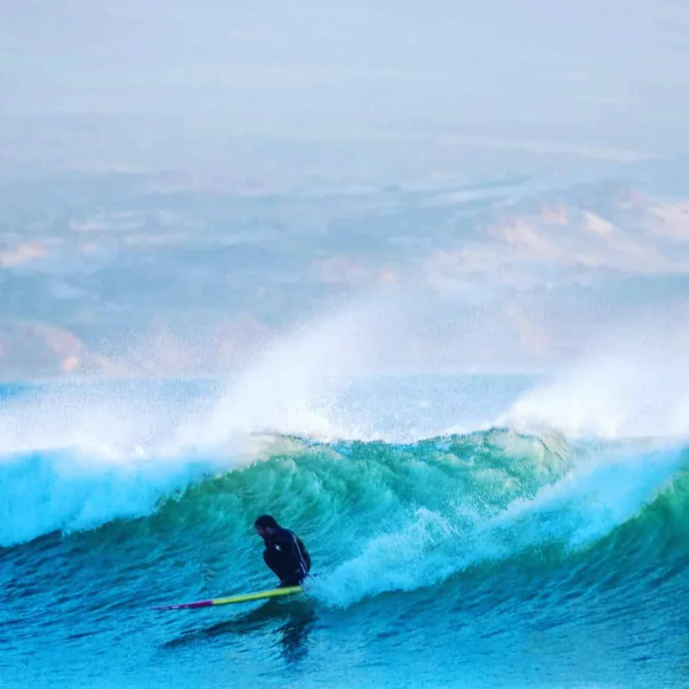 Un surfeur glissant sous la lèvre d’une vague qui casse.
