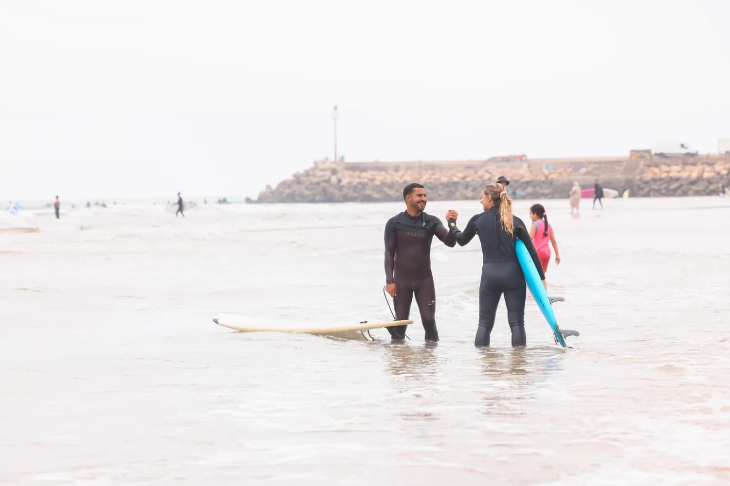 Deux surfeurs souriant ensemble dans peu d’eau après une session.