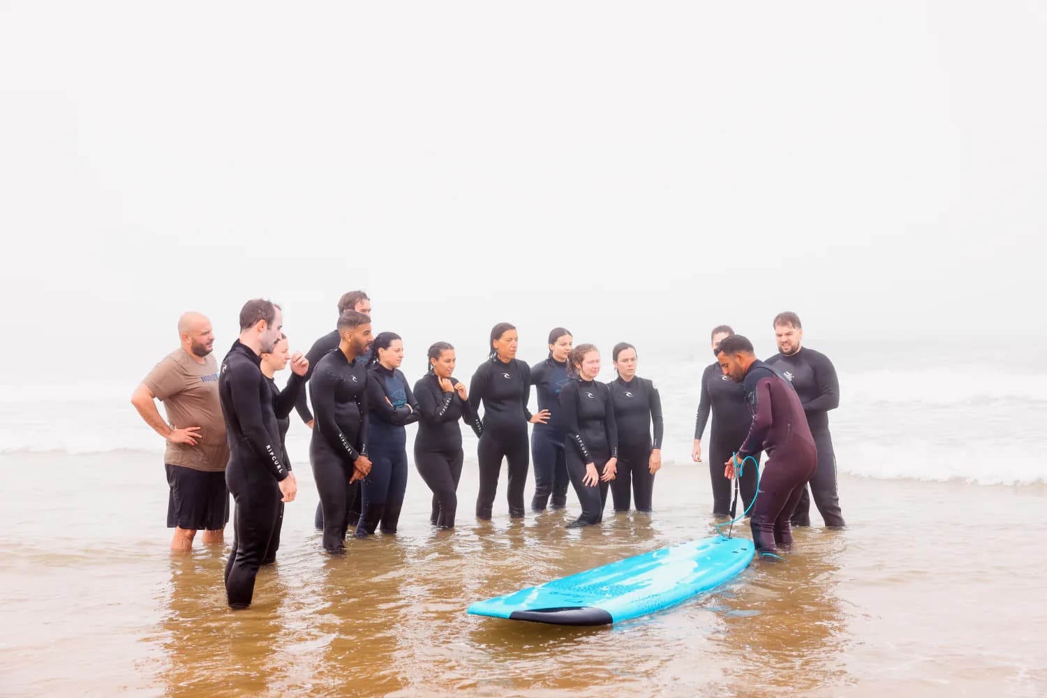 Un groupe de cours rassemblé autour de planches bleues sur le sable mouillé.