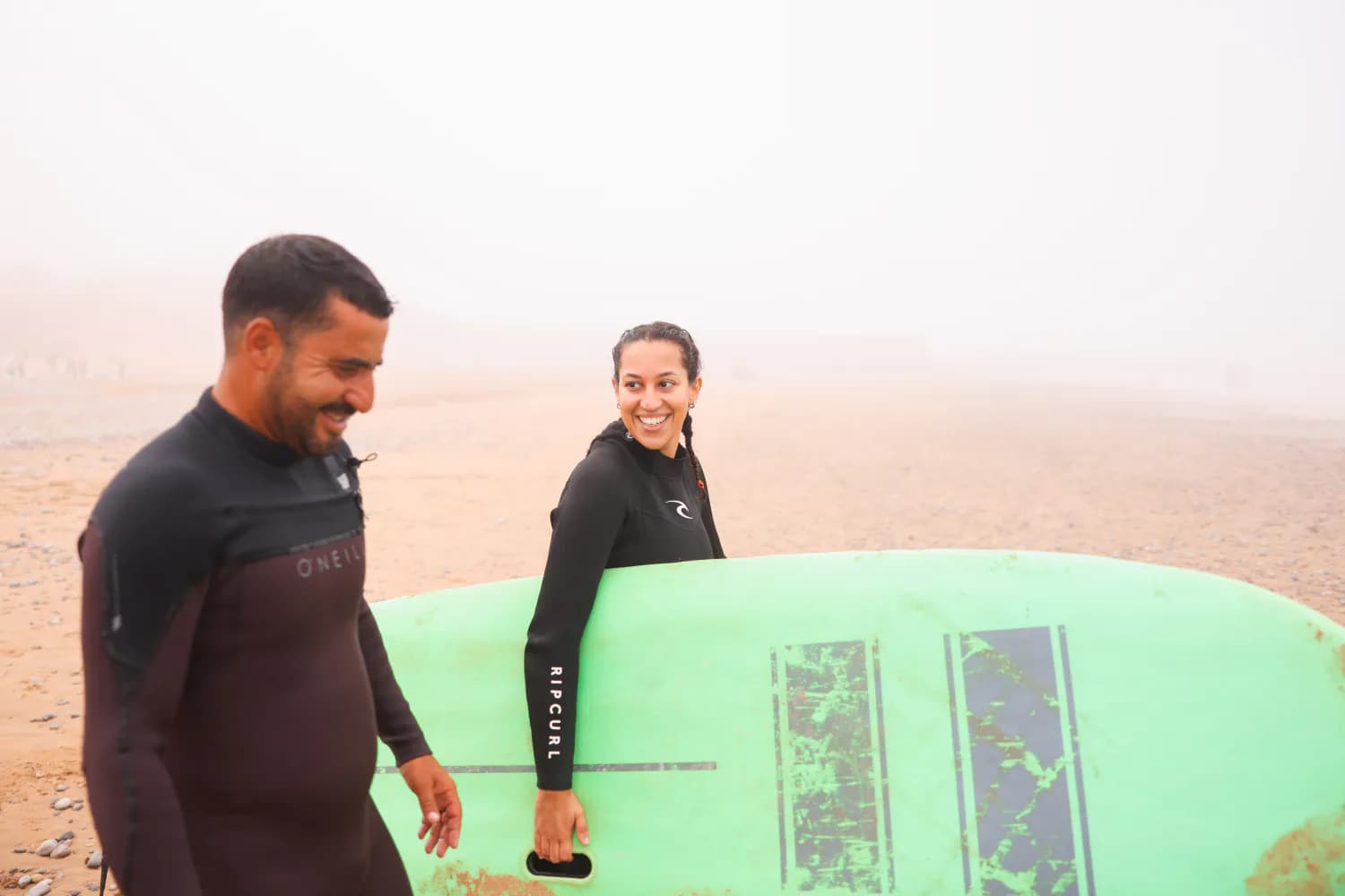 Un moniteur et une élève souriant à côté d’une planche verte.